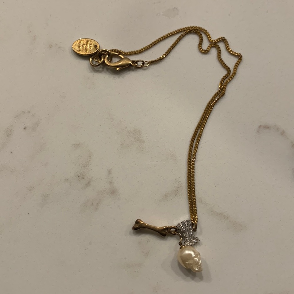 Gold necklace with skull, bone, and bow